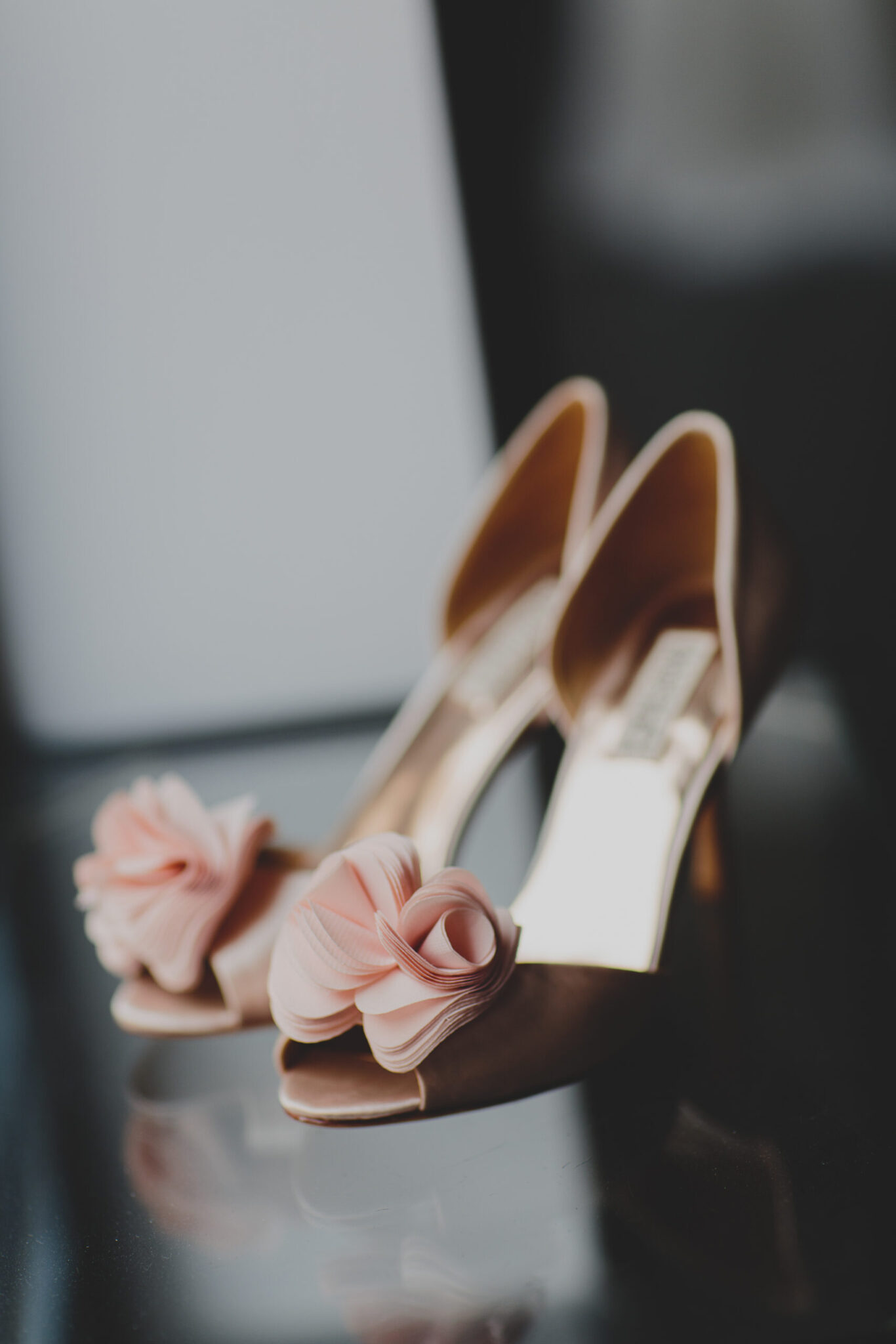 Nahaufnahme von eleganten High Heels mit rosafarbener Stoffblumenverzierung an den Zehen, perfekt um Ihren Brautlook zu vervollständigen. Entdecken Sie einzigartige Accessoires wie diese in Second Hand Brautkleider Shops für Brautmode in Stuttgart.